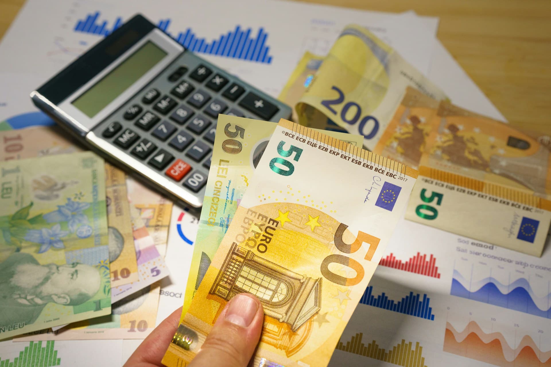 Obrazek przedstawiający biurko, na którym leżą dokumenty, kalkulator oraz banknoty euro